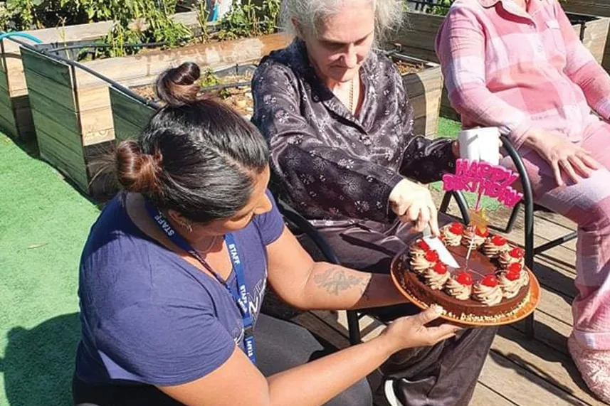 Staff bringing out a birthday cake in the Shine House garden