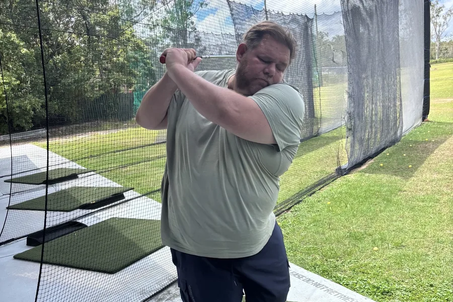 A participant mid-swing at a golf driving range