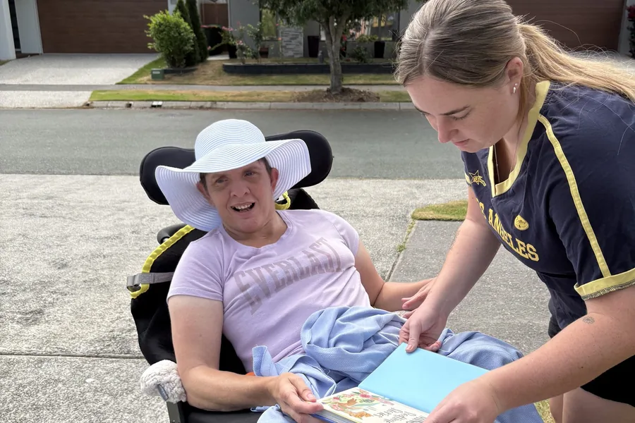 A support worker reading through a book with a participant outdoors